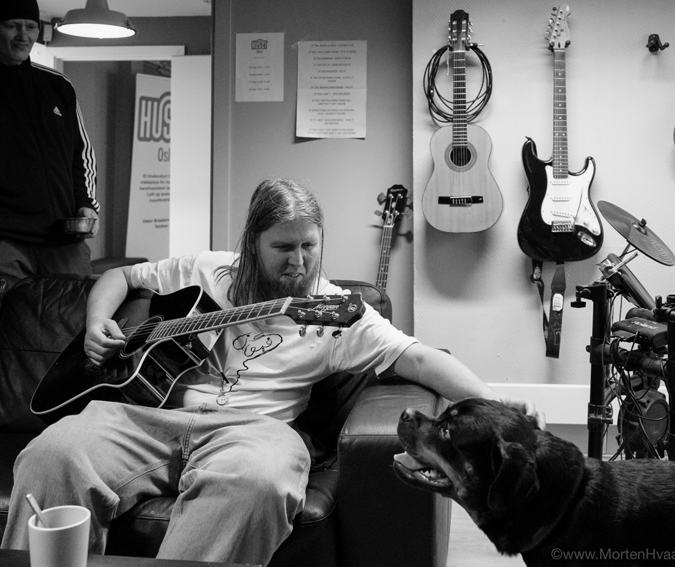 person med gitar som klapper hund hos Huset Oslo. Foto: Morten Hvaal